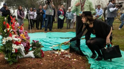 Phoebe Parker, derecha, coloca flores durante la ceremonia de entierro de restos cremados de muertos que no fueron reclamados.