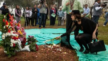 Phoebe Parker, derecha, coloca flores durante la ceremonia de entierro de restos cremados de muertos que no fueron reclamados.