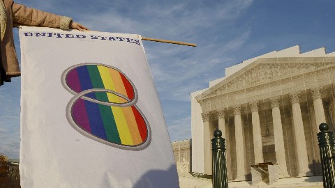 Una manifestante que favorece los matrimonios entre personas del mismo sexo levanta una bandera gay frente a la Corte Suprema.