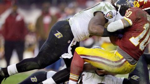 Robert Griffin III de los Pieles Rojas es interceptado por Courtney Upshaw de los Cuervos.