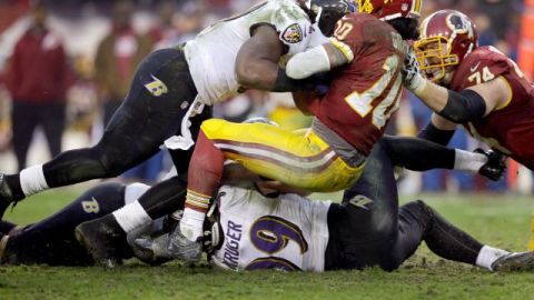 Robert Griffin III de los Pieles Rojas es interceptado por Courtney Upshaw de los Cuervos.