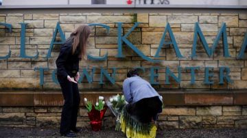 Dos personas colocan flores en homenaje a las víctimas del tiroteo en el centro comercial Clackamas Town Center, en un suburbio de Portland, Oregon.