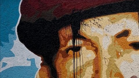 Un hombre camina junto a un mural del presidente venezolano, Hugo Chávez, en una calle de Caracas, Venezuela.