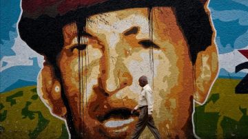 Un hombre camina junto a un mural del presidente venezolano, Hugo Chávez, en una calle de Caracas, Venezuela.