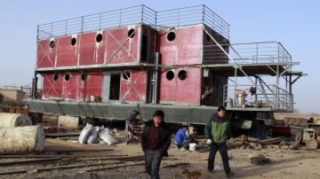 En esta foto tomada en noviembre, el ciudadano chino Lu Zhenghai -a la derecha- en el lugar donde construía la nave que lo salvaría junto a su familia en caso de que el 21 de diciembre se acabe el mundo.