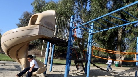 Niños juegan en el parque que está siendo cambiado a uno de acceso total para niños con problemas físicos en Pacoima.