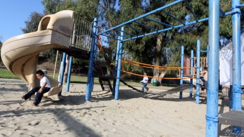 Niños juegan en el parque que está siendo cambiado a uno de acceso total para niños con problemas físicos en Pacoima.
