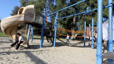 Niños juegan en el parque que está siendo cambiado a uno de acceso total para niños con problemas físicos en Pacoima.