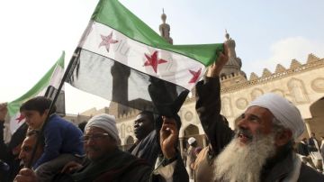 Varias personas protestan en la mezquita Al Azhar en El Cairo (Egipto) con una bandera de la revolución siria a favor del pueblo sirio, ayer.
