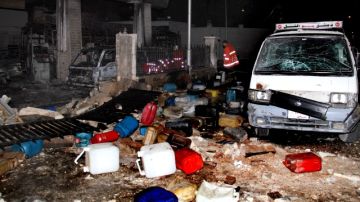 Un policía sirio inspecciona daños causados en estación de gasolina por explosión de carro-bomba en Barzeh, Damasco (Siria).