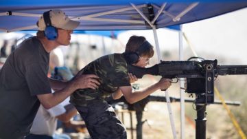 Steve Dillon (izq.) sostiene a su hijo George (c), de 10 años, mientras el muchacho dispara una ametralladora M240, en Arizona.