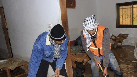 Voluntarios palestinos ayudan a familia que tiene la vivienda anegada de agua debido a inundaciones por el temporal que azota la zona.