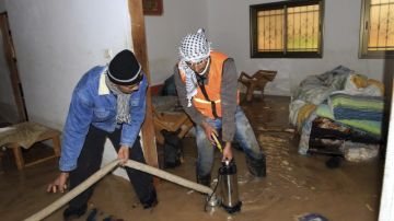 Voluntarios palestinos ayudan a familia que tiene la vivienda anegada de agua debido a inundaciones por el temporal que azota la zona.