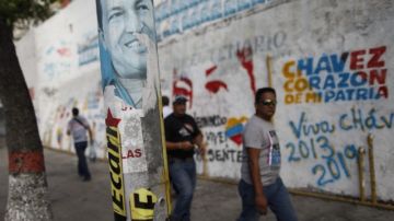 Transeúntes caminan frente a pintadas de apoyo al presidente Hugo Chávez, ayer, en el centro de Caracas (Venezuela).