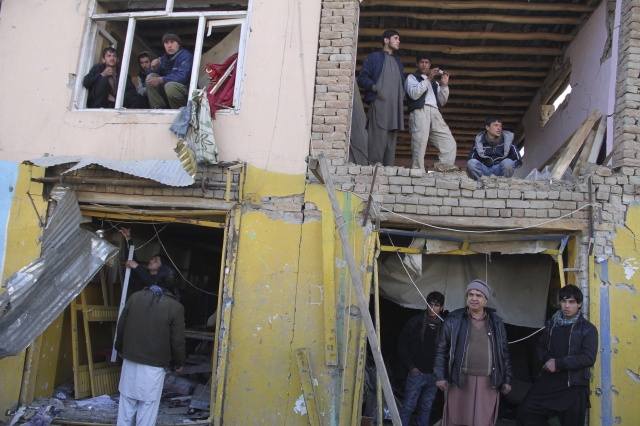 Varias personas inspeccionan un edificio en el lugar donde se ha producido un atentado en Kabul, en Afganistán.