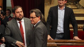 El líder de ERC, Oriol Junqueras (i), le da la mano al presidente de la Generalitat, Artur Mas (d), observados ambos por el líder de ICV-EUiA, Joan Herrera (d), tras la votación en el Parlamento.