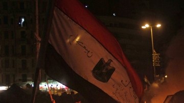 Manifestantes egipcios  frente a vehículo de las fuerzas de seguridad en llamas, mientras  disturbios siguen en el  El Cairo, a pesar de las medidas de emergencias y toque de queda que ordenó el Presidente.