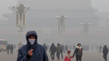 Un hombre usa una máscara para cubrirse de la contaminación mientras camina por la plaza de Tiananmen, en Pekín.