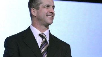El coach de los Cuervos, John Harbaugh (izq.) y  el de los 49ers, su hermano Jim Harbaugh, sonríen antes de iniciar la rueda de prensa.