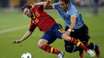 El español Juan Mata (izq.) pelea un balón con el uruguayo  Martín Cáceres en el encuentro de ayer que se celebró  en Qatar.