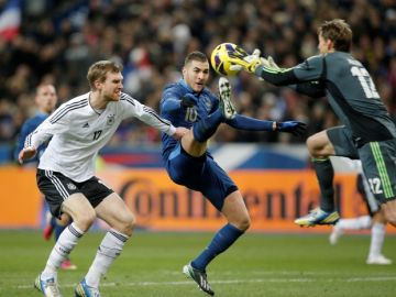 El alemán Per Mertesacker (izq.) y su portero  Rene Adler defienden su meta ante el acoso del delantero francés   Karim Benzema.