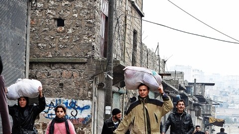 Algunos  caminaban ayer en Alepo, Siria, con sus  pertenencias tras cruzar un río que dividía a elementos del ejército sirio de los combatientes  opositores al régimen.