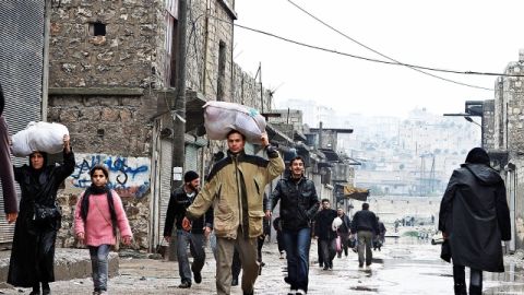 Algunos  caminaban ayer en Alepo, Siria, con sus  pertenencias tras cruzar un río que dividía a elementos del ejército sirio de los combatientes  opositores al régimen.