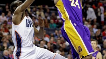 Kobe Bryant suelta un disparo a la canasta ante el acoso de Kemba Walker, de los Bobcats de Charlotte.