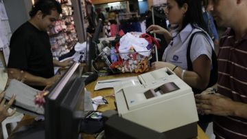 Venezolanos pagan sus compras en una tienda,  en el centro de Caracas. Desde ayer entra en vigor en el país la devaluación en la tasa de cambio oficial del bolívar con el dólar, lo cual ha creado el riesgo de la inflación y la gente está temerosa.