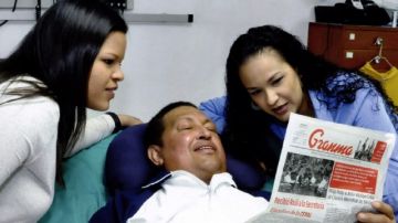 El presidente de Venezuela, Hugo Chávez, junto a sus hijas Rosa Virginia (der.) y María Gabriela (izq.) leyendo el diario oficialista 'Gramna', en La Habana, Cuba.