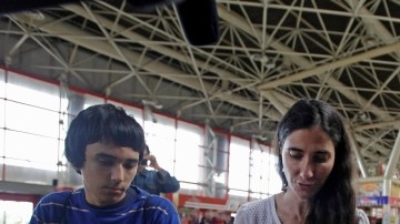 La disidente cubana Yoani Sánchez muestra su pasaporte delante de los fotógrafos antes de tomar el avión que la llevaría a Brasil.