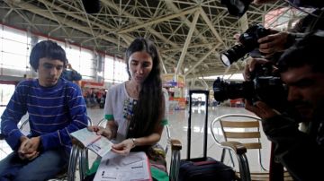 La disidente cubana Yoani Sánchez muestra su pasaporte delante de los fotógrafos antes de tomar el avión que la llevaría a Brasil.