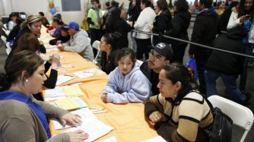 Familias reciben asistencia para llenar sus solicitudes de seguro médico en la  reciente feria  de WE Connect, en Fresno, Calif.