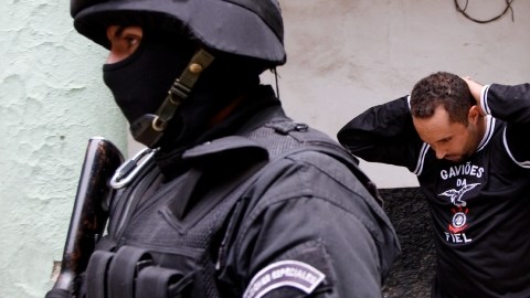 Un hombre identificado como aficionado del Corinthians es escoltado por policías bolivianos al interior de una prisión en La Paz.