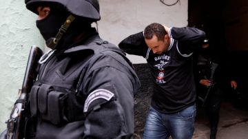 Un hombre identificado como aficionado del Corinthians es escoltado por policías bolivianos al interior de una prisión en La Paz.