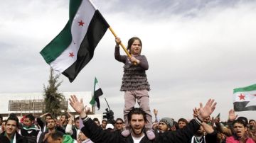Una niña, subida a su padre, ondea una bandera siria en protesta contra Al Asad, ante  embajada siria de Amán, Jordania, ayer.