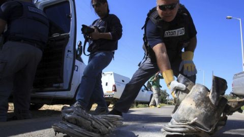 Un zapador de policía israelí recogía ayer los restos de un cohete que cayó junto a una carretera de Ashquelón, al sur de Israel.