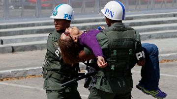 Oficiales venezolanos tuvieron que auxiliar a esta mujer que se desmayó mientras hacía la fila para dar su último adiós al presidente Chávez.
