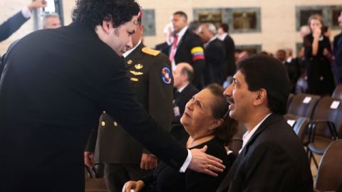 El maestro Gustavo Dudamel toca el hombro de Elena Frías, madre del presidente venezolano Hugo Chávez, mientras su otro hijo Argenis mira al director de orquesta en la ceremonia del funeral.