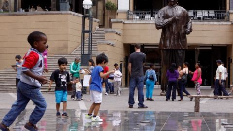 Varios niños juegan cerca de una estatua del expresidente sudafricano Nelson Mandela en Sandton, una localidad de Johanesburgo.