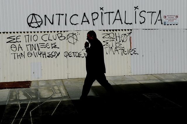 Un hombre camina junto a un mensaje anticapitalista en el centro de Nicosia en Chipre hoy, 19 de marzo de 2013.