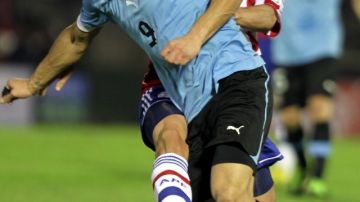 El jugador paraguayo Cristian Riveros (atrás) marca al uruguayo Luis Suárez, durante el partido en el Estadio Nacional de Montevideo.