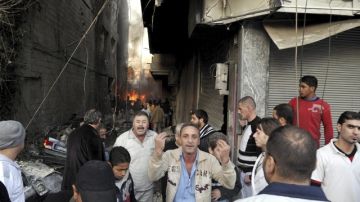 Un grupo de sirios observan el escenario de destrucción por un ataque con coche-bomba en Yarmana,  Damasco, Siria.