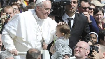 El papa Francisco, en su primera celebración de Semana Santa, bendice a una niña cuando saluda a los fieles al final del Domingo de Ramos, en la Plaza de San Pedro, ayer.