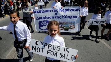 Estudiantes llevan un rótulo que dice 'Chipre no está en venta' mientras participan en un desfile en Limassol, Chipre.
