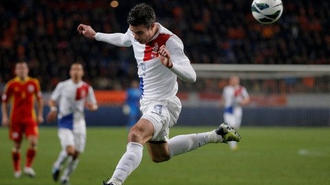 El holandés  Robin van Persie cabecea el balón, mientras lo espera el  arquero de Rumania, Costel Fane.