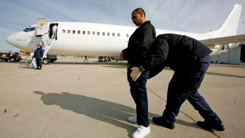 Un agente chequea a un inmigrante antes de que este sea deportado a México.en un vuelo desde Chicago.