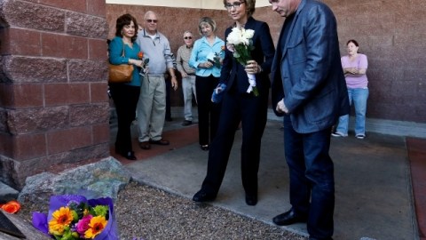 La excongresista Gabrielle Giffords (c), con su esposo, Mark Kelly, visitan el lugar donde ocurrió el ataque.