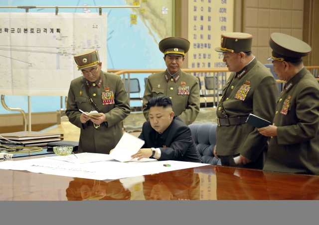 El líder norcoreano, Kim Jong-un (c), durante una reunión en la madrugada de este viernes en un lugar indeterminado, en la que ordenó tener preparados sus misiles para atacar en "cualquier momento" intereses de EEUU y Corea del Sur.