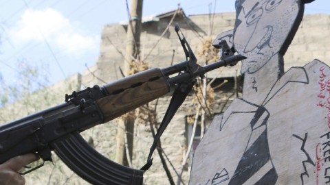 Apuntan con un arma a la figura  de Al Assad,   en Alepo, ayer.